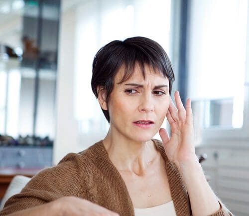 Women suffering from tinnitus touching her ears