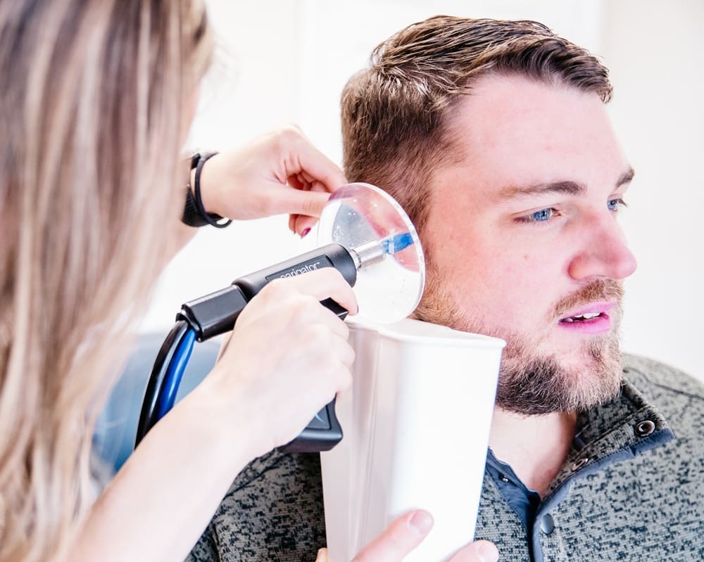 Hearing professional performing earwax extraction on a kid